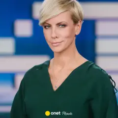 Anita Werner w zielonej sukience, z krótkimi blond włosami, na tle niebiesko-białej grafiki.