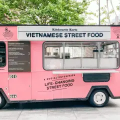 Un food truck rosa brillante, "Kitchenette Karts", offre "Vietnamese Street Food" e cibo che cambia la vita.