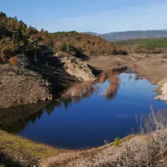 Le lac de Meaulx, aux reflets bleus intenses, est entouré de collines boisées aux couleurs d'automne.