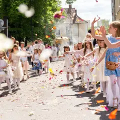 Dzieci sypią kwiaty na procesję. 8 czerwca święto, radosna atmosfera.