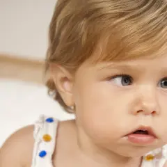Primo piano di un neonato con occhi chiari. Uno sguardo attento, forse un caso di falso strabismo nei neonati, che spesso si risolve da solo.