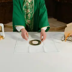 Kapłan przygotowuje się do udzielenia komunii. Na ołtarzu kielich, patena z hostią i księga.
