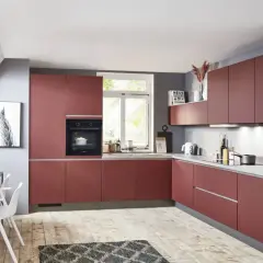 Cocina moderna y alargada con gabinetes rojos, encimeras grises y suelo de madera. Perfecta para distribuir tu espacio.