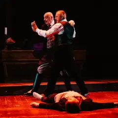 Dwóch mężczyzn tańczy tango na scenie, podczas gdy trzeci leży na podłodze. Edek Tango w akcji.