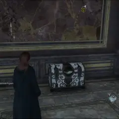 W Hogwart's Legacy, skrzynia z okiem czeka na odkrycie. Jej wzór przyciąga wzrok, a zielone oko zdaje się obserwować gracza.
