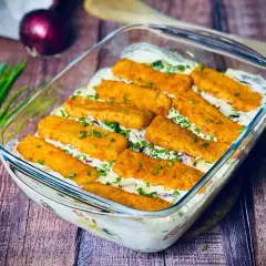 Ausgefallene Gerichte: Fischstäbchen-Auflauf mit cremiger Soße und frischen Kräutern, garniert mit Schnittlauch.