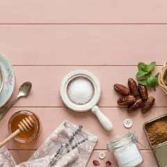 Stevia, miód, daktyle, cukier i syrop klonowy – co jest zdrowsze od cukru? Kompozycja na różowym tle.