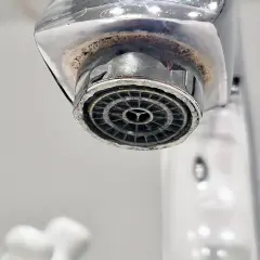 Zakamieniony perlator kranu z widocznym osadem wapiennym.