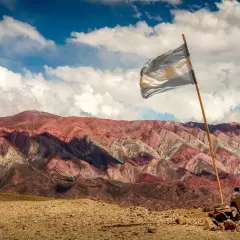 Argentyńska flaga powiewa na tle kolorowych gór i pickupa.