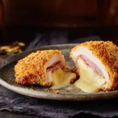 Un cordon bleu coupé en deux, révélant un fromage fondant et du jambon. Le secret d'un bon quel fromage pour cordon bleu réside dans sa texture crémeuse.