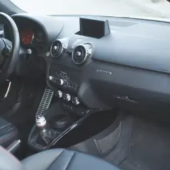 Vue de l'intérieur d'une Audi A1, avec le volant, la console centrale et les sièges en cuir noir.