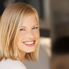 Lächelnde Frau mit blondem Bob, ein moderner **haarschnitt frauen**. Ihr Blick ist strahlend, die Haut makellos.