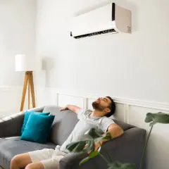 Un homme se repose sur un canapé sous la climatisation, ignorant les effets néfastes de la climatisation sur la santé et l'environnement.