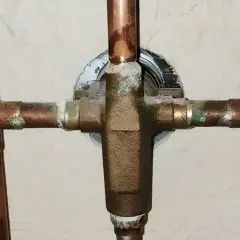 Plomberie en cuivre avec dépôts verts, signe des inconvénients de l'eau trop douce qui corrode le métal.