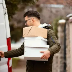 Kurier z kilkoma paczkami, gotowy do załadunku do białego vana. Kolejna paczka do Islandii w drodze!