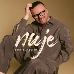 Gigi D'Alessio sorride, con la mano tra i capelli. Sulla sua camicia, la scritta "Nuje". Chissà cosa ci spiegate cherè.