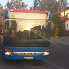 Niebieski autobus Setra z Giżycka do Olsztyna, sprawdzam express bus Giżycko Olsztyn cena. Słońce odbija się w szybie.