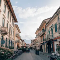 Strada pittoresca a Forte dei Marmi, Italia, con palazzi color pastello, balconi in ferro battuto e biciclette parcheggiate.