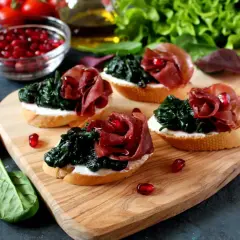 Leckere Bruschetta mit Spinat, Schinken und Granatapfelkernen – eine tolle Kombination eisenhaltiger Lebensmittel.