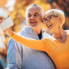 Szczęśliwa para robi selfie na tle jesiennych liści. Czas na emerytury pomostowe nowości i wspólne chwile.
