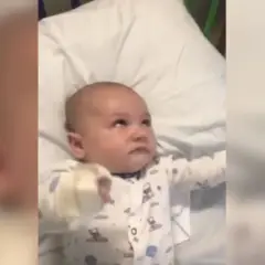 Bebé en pijama con patrones de nubes y lunas, con la mirada perdida, podría estar experimentando espasmos infantiles.