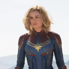 Captain Marvel, en armure bleue et rouge, prête à défendre la Terre. Elle est la réponse à qui est Captain Marvel.
