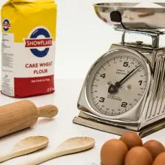 Mąka, waga kuchenna, wałek i jajka na białym tle.