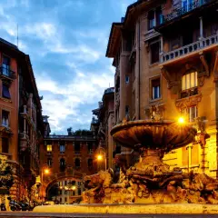 Fontana e palazzi illuminati a Roma, quartiere Coppedè cosa vedere. Atmosfera magica al crepuscolo.