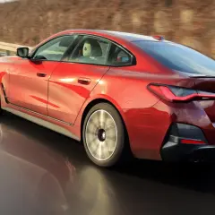 Czerwone BMW 4 Gran Coupé pędzi po zakręcie drogi, ukazując dynamiczną sylwetkę i sportowe felgi.