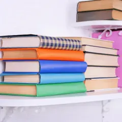 Stos kolorowych książek na półce. Czytanie między wierszami odmowy, jak objawy odrzucenia maszynopisu, bywa trudne.