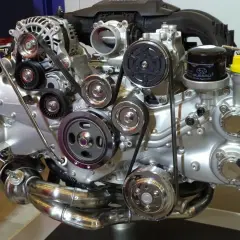 Błyszczący silnik Subaru z paskami, kołami pasowymi i filtrem oleju. Widać tu wiele elementów, w tym jeden duży cylinder.