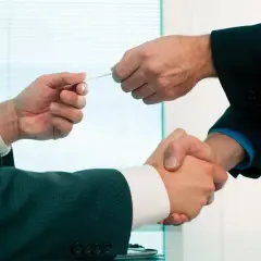 Dwóch biznesmenów wymienia się wizytówkami, co to jest wiron? To symbol nawiązywania kontaktów i współpracy.
