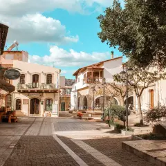 Malia, Kreta: malerische Gasse mit Cafés und traditionellen Gebäuden unter blauem Himmel.
