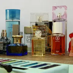 Różne flakoniki perfum i wód toaletowych na drewnianym blacie.