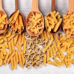 Różnorodne kształty makaronu, od penne po serduszka i kokardki, prezentują bogactwo produkcji makaronu.