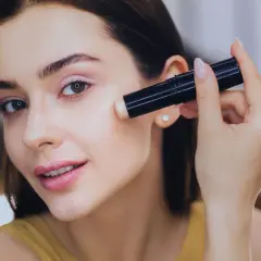 Donna applica il correttore, assicurandosi che il correttore deve essere più chiaro del fondotinta per un look luminoso.