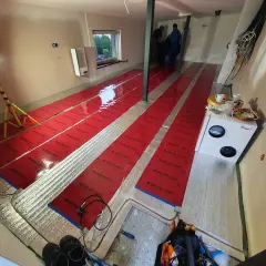 Instalacja folii grzewczej "Dream Heat" na podłodze. Czy folia grzewcza jest oszczędna? Montażyści pracują, przygotowując pomieszczenie do ogrzewania.