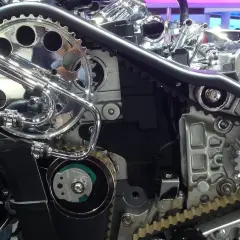 Mécanisme complexe de moteur avec courroie crantée, poulies chromées et tuyaux. Ce système, s'il est défectueux, peut causer un bruit de courroie de distribution.