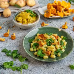 Pyszny obiad z ziemniaków: kluseczki z kurkami i zieloną pietruszką, obok miseczka curry i świeże kurki.