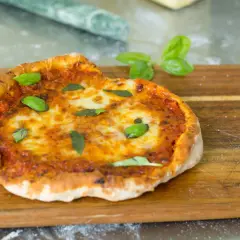 En perfekt pizza i airfryer, med smält ost och färsk basilika, serverad på en träskärbräda.