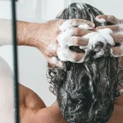 Persona disfrutando de un relajante lavado de cabeza con abundante espuma de champú.
