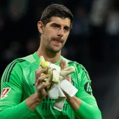 Thibaut Courtois w zielonej koszulce bramkarskiej, trzymający rękawice, z wyrazem twarzy sugerującym ból po kontuzji.
