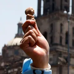 Hand hält Fötus-Figur vor Kirche. Debatte um evangelische Kirche und Abtreibung.