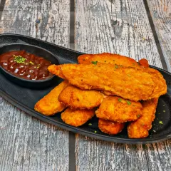 Chrupiący kurczak w panko, podany z sosem barbecue na czarnej tacy. Idealna przekąska.