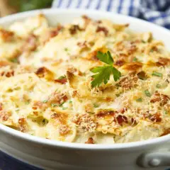 Un plat de tartiflette gratinée, garni de lardons et de persil, prêt à être dégusté avec un bon vin.
