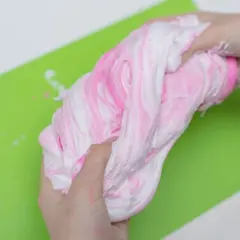 Ręce ugniatają różowo-biały slime, pokazując, jak zrobić slime z kleju i aktywatora.