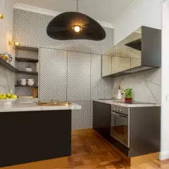 Cucine piccole ma eleganti, con piano in marmo, pensili a specchio e un'originale lampada a sospensione.