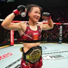 UFC strawweight champion celebrates victory, flexing her muscles and holding a drink can.