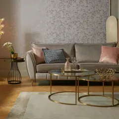 Przytulny salon glamour z szarą sofą, różowymi poduszkami i złotymi dodatkami.