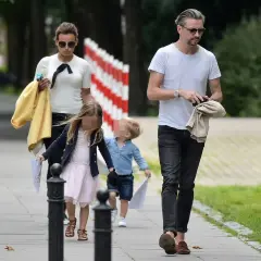 Anna Mucha z dziećmi spaceruje po chodniku. Dziewczynka w różowej sukience i chłopiec w niebieskiej koszuli idą obok.